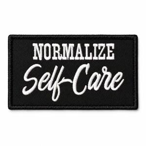 May include: A rectangular black embroidered patch with a stitched border. The text NORMALIZE is embroidered in white block letters on the top line, and the words Self-Care are embroidered in white cursive script on the bottom line.