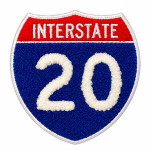 May include: A shield-shaped embroidered patch featuring a red top section with the white text INTERSTATE and a blue lower section with the large white number 20. The entire patch is outlined with a white stitched border on a white background.