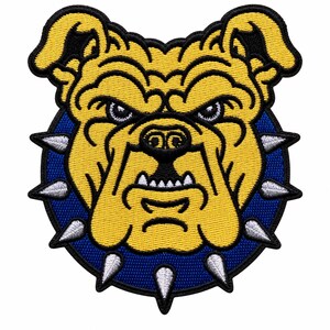 May include: An embroidered patch featuring the head of a yellow bulldog with a stern expression. The bulldog wears a dark blue spiked collar. The design is circular with a black border, showcasing detailed stitching in yellow, blue, and silver.