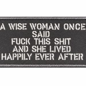 May include: A rectangular black embroidered patch with a stitched border. The white text reads: A WISE WOMAN ONCE SAID FUCK THIS SHIT AND SHE LIVED HAPPILY EVER AFTER. The design features bold, block-style lettering centered on the fabric surface.