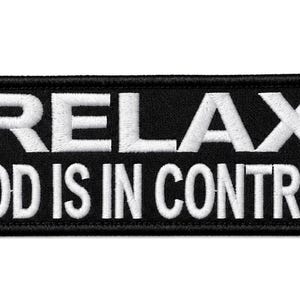 May include: A rectangular black embroidered patch with a thick black border. The patch features the white embroidered text RELAX on the top line and GOD IS IN CONTROL on the bottom line in a bold, sans-serif, all-caps font style.