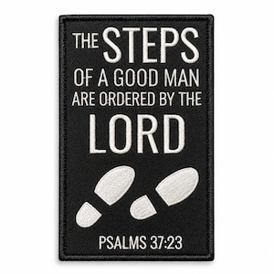 May include: A rectangular black embroidered patch featuring white text that reads THE STEPS OF A GOOD MAN ARE ORDERED BY THE LORD and PSALMS 37:23, with two white embroidered footprints positioned between the text lines.