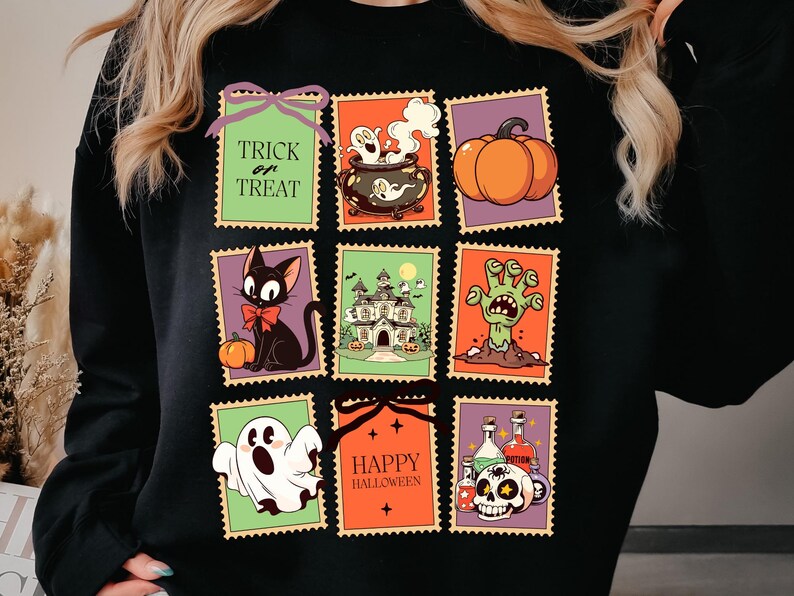 May include: Black sweatshirt featuring a colorful Halloween-themed design. The design includes various illustrations within postage stamp-like frames, such as a black cat, pumpkin, haunted house, zombie hand, ghost, cauldron, and skull with potion bottles. Text includes "Trick or Treat" and "Happy Halloween."