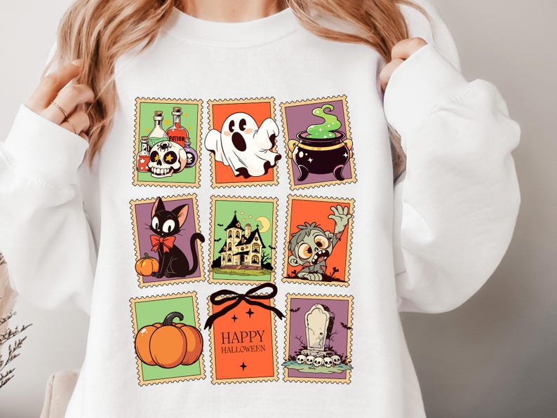 May include: White sweatshirt featuring a colorful Halloween-themed design. The design includes various illustrations such as a skull, ghost, cauldron, black cat, haunted house, zombie, pumpkin, and the text "Happy Halloween".