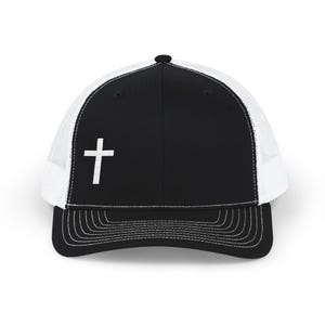 Peut inclure: Une casquette de type trucker noire et blanche avec un panneau avant noir uni orné d'une croix blanche brodée sur le côté gauche, une visière noire à surpiqûres blanches et un panneau arrière en maille blanche avec un bouton noir.