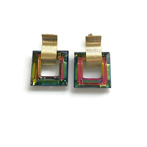 May include: A pair of gold earrings with iridescent square-shaped crystals. The earrings have a gold bar that wraps around the crystal.