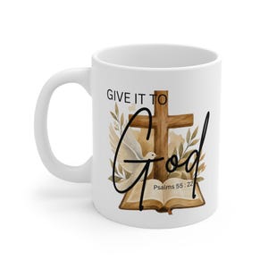 May include: A white ceramic mug featuring a watercolor illustration of a brown wooden cross, an open book, and a white dove surrounded by foliage. The text reads "GIVE IT TO God" in black lettering, with "Psalms 55 : 22" printed below the book.