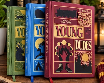 Puede incluir: Tres libros de tapa dura titulados All The Young Dudes de Ms. King Bean. Las portadas verde, azul y granate presentan ilustraciones gráficas en oro y negro que incluyen un tren, un reloj, un ciervo, una tienda de campaña, fases lunares y botas.