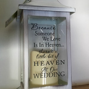 May include: White lantern with a glass panel featuring the text "Because Someone We Love Is In Heaven... there's a little bit of HEAVEN At Our WEDDING".