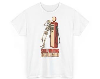 Ein freches Skelett, das neben einer Zapfsäule zusammengesunken sitzt – Lustiges Halloween-T-Shirt mit Grafik (Unisex)