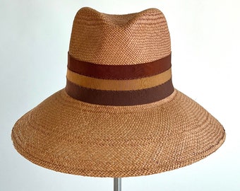 Bold, honey-colored panama straw hat with a tall crown and wide brim, adorned with earth-toned multi-colored grosgrain wide ribbon trim