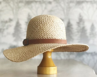 Parker: Round crown double raffia natural straw hat with east/west floppy brim with natural vegetable tanned leather of antique brass buckle