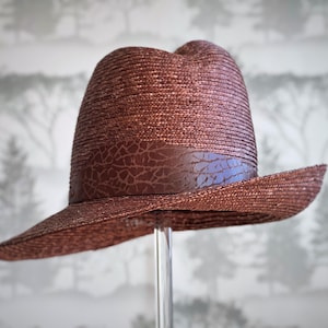 Brown straw hat with side upturn brim and asymmetrical crown with leather band