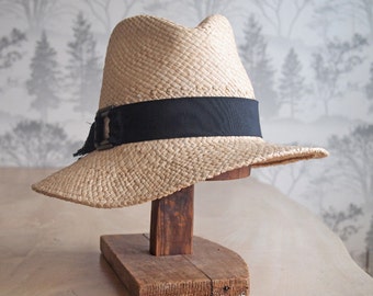 Zoe II: Made of natural doubled raffia with tall trilby crown and sloping east to west brim with black trim