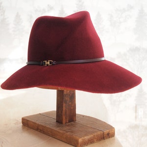 Elle: Cross front tribly crown with floppy soft brim of burgundy velour fur felt with matching leather trim and antique brass finding