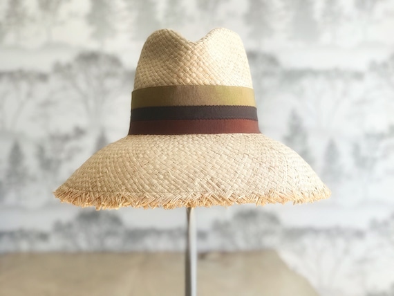 Rich earth tone striped natural raffia straw sun hat with wide bell shaped brim with fringed edge