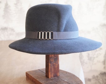 Bette: Smoke gray fedora with front crease in velour fur felt with french beauvais grosgrain ribbon and antique silver chain finding.