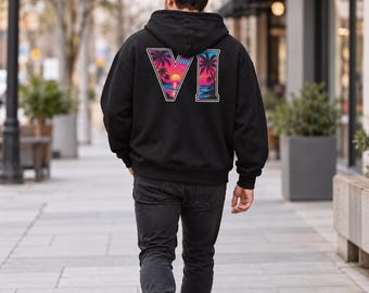 Peut inclure: Un sweat-shirt à capuche noir avec un grand motif au dos représentant le chiffre romain VI. Les lettres sont remplies d'une scène de coucher de soleil vibrante, incluant des silhouettes de palmiers, un soleil brillant et une plage en rose et bleu.