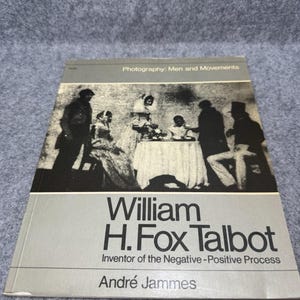 May include: A softcover book titled William H. Fox Talbot: Inventor of the Negative-Positive Process by André Jammes. The cover features a black and white historical photograph of people around a table and the text Photography: Men and Movements.