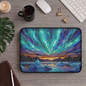 May include: A rectangular laptop sleeve featuring a vibrant stained glass pattern of the aurora borealis above dark mountain silhouettes and a reflective icy landscape in shades of teal, deep blue, purple, and orange with a black zipper border.