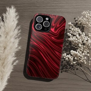 Capa resistente para celular com efeito iridescente vermelho, acabamento metálico brilhante e textura ondulada acetinada, ideal para iPhone, Samsung Galaxy e Google Pixel. Um presente de luxo.