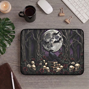 Peut inclure: Une housse d'ordinateur portable rectangulaire ornée d'une illustration gothique sombre représentant un corbeau noir perché sur une pile de livres, entouré de crânes humains, de roses rouges et d'arbres dénudés sous une pleine lune.