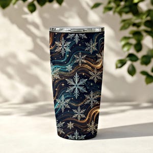 May include: A cylindrical stainless steel tumbler featuring a dark navy blue background with swirling gold and teal wave patterns, decorated with numerous white and silver snowflake illustrations and small sparkling star accents.