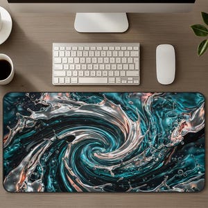 May include: A rectangular desk mat featuring a swirling water design in shades of teal, silver, and orange. The mat is placed on a wooden desk, with a keyboard, mouse, and monitor visible.