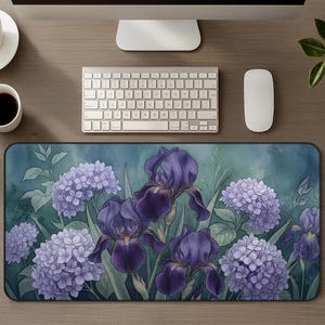 May include: A rectangular desk mat featuring a watercolor-style illustration of deep purple iris flowers and clusters of light purple hydrangea blossoms set against a dark teal and blue-green background with green foliage and stems.
