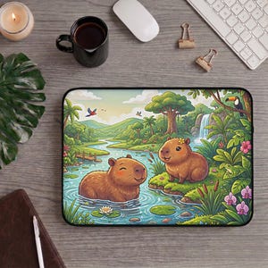May include: A rectangular laptop sleeve featuring a colourful illustration of two brown capybaras in a tropical river landscape with lush green trees, a waterfall, vibrant flowers, and various birds, all set against a light-coloured sky background.