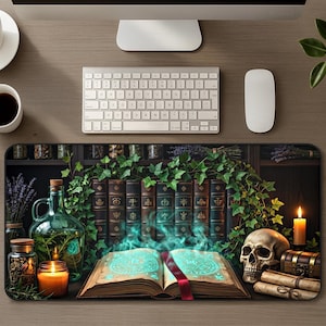 May include: A rectangular desk mat featuring an open book with glowing blue magical symbols, surrounded by a human skull, a lit candle, a glass bottle with herbs, a small wooden chest, and rolled parchment scrolls, all set against a bookshelf.
