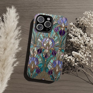 May include: A phone case featuring a stained-glass design with irises in shades of purple, teal, and gold. The case has a glossy finish and a camera cutout. The floral pattern is reminiscent of Art Nouveau.
