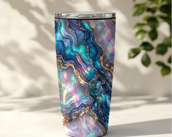 Könnte beinhalten: Ein zylindrischer Becher mit einem lebendigen, wirbelnden Marmormuster in Schattierungen von tiefem Blau, Türkis und schillerndem Violett, akzentuiert durch dünne, metallisch goldene Adern, die ein geodenartiges Aussehen auf der Oberfläche erzeugen.