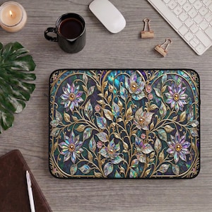 May include: A decorative laptop sleeve featuring a floral design with gold-colored accents. The design includes iridescent flowers and leaves on a dark teal background. The sleeve has a black border and a zipper closure.