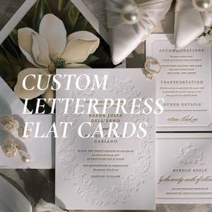 May include: A collection of white letterpress wedding stationery featuring gold foil text, including an invitation with an ornate embossed border, an accommodations card, and a reply card, accented by a gold ring and white satin shoes.