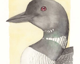 May include: Watercolor painting of a loon's head and neck, set against a pale yellow background. The bird has a dark gray head, a long black beak, and a red eye. The neck features white and gray striped patterns.