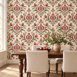 Puede incluir: Papel pintado con un patrón repetitivo de granadas rojas y follaje verde sobre un fondo crema. Una mesa de comedor de madera con un cuenco de granadas y un jarrón con flores se sitúa frente a la pared, acompañada por dos sillas tapizadas.