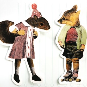 May include: Two whimsical die-cut stickers featuring anthropomorphic animals. One is a squirrel in a pink dress and party hat, the other a fox in a striped shirt and shorts. The squirrel sticker has the text "pergamo paper goods".