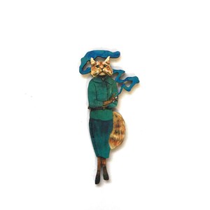 May include: A wooden figurine of a cat wearing a teal blue jacket and skirt, with a cigarette in its paw and blue smoke coming from its mouth.