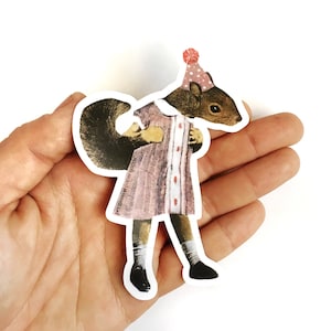 May include: A sticker of a squirrel wearing a pink dress and a party hat. The squirrel is standing on its hind legs and has its arms crossed. The sticker is on a hand.