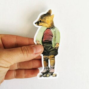 May include: A sticker featuring a fox-headed character wearing a red striped shirt, green jacket, and striped shorts, standing on roller skates. The sticker is held by a hand against a white background.