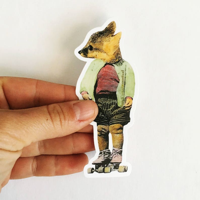 May include: A sticker featuring a fox-headed character wearing a red striped shirt, green jacket, and striped shorts, standing on roller skates. The sticker is held by a hand against a white background.