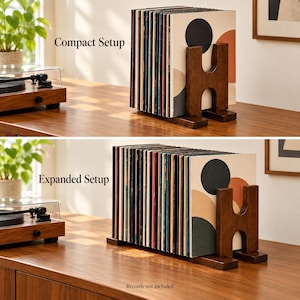 May include: A dark brown wooden vinyl record storage stand featuring an H-shaped support structure. The image displays two configurations labeled Compact Setup and Expanded Setup, holding multiple vinyl records with abstract circular designs.