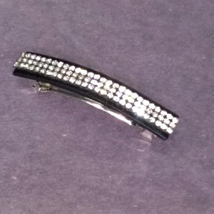 May include: Black hair clip with a row of clear rhinestones.