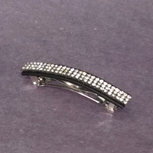 May include: A black and silver hair clip with a row of clear rhinestones.