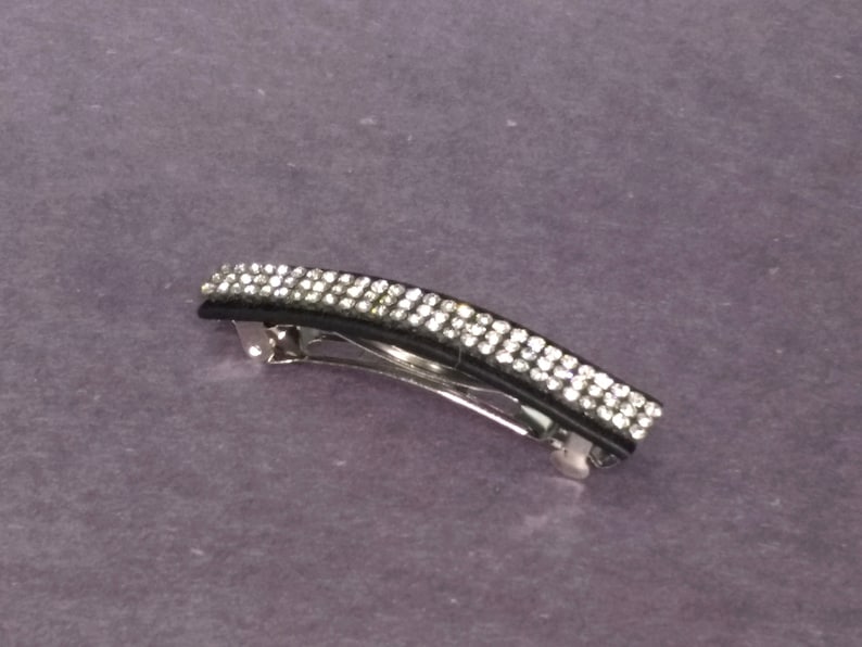 May include: A black and silver hair clip with a row of clear rhinestones.
