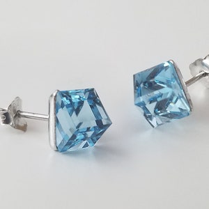 May include: A pair of silver stud earrings with square shaped blue topaz gemstones.