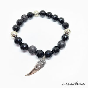 May include: Black gemstone bracelet with silver beads and a silver wing charm.