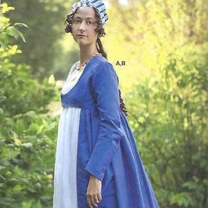 May include: A woman wearing a white and blue striped hat and a blue dress with a white underskirt. The dress has a scoop neckline and long sleeves. The woman is standing in a garden with green foliage.