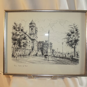 May include: A black and white ink drawing of a church and obelisk in Rome, Italy. The drawing is framed in a silver frame. The text "Roma, Trinita de Monti" is at the bottom of the drawing.